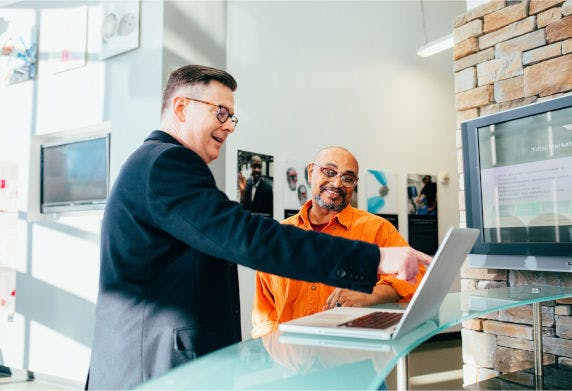 Two men smiling a computer in an office